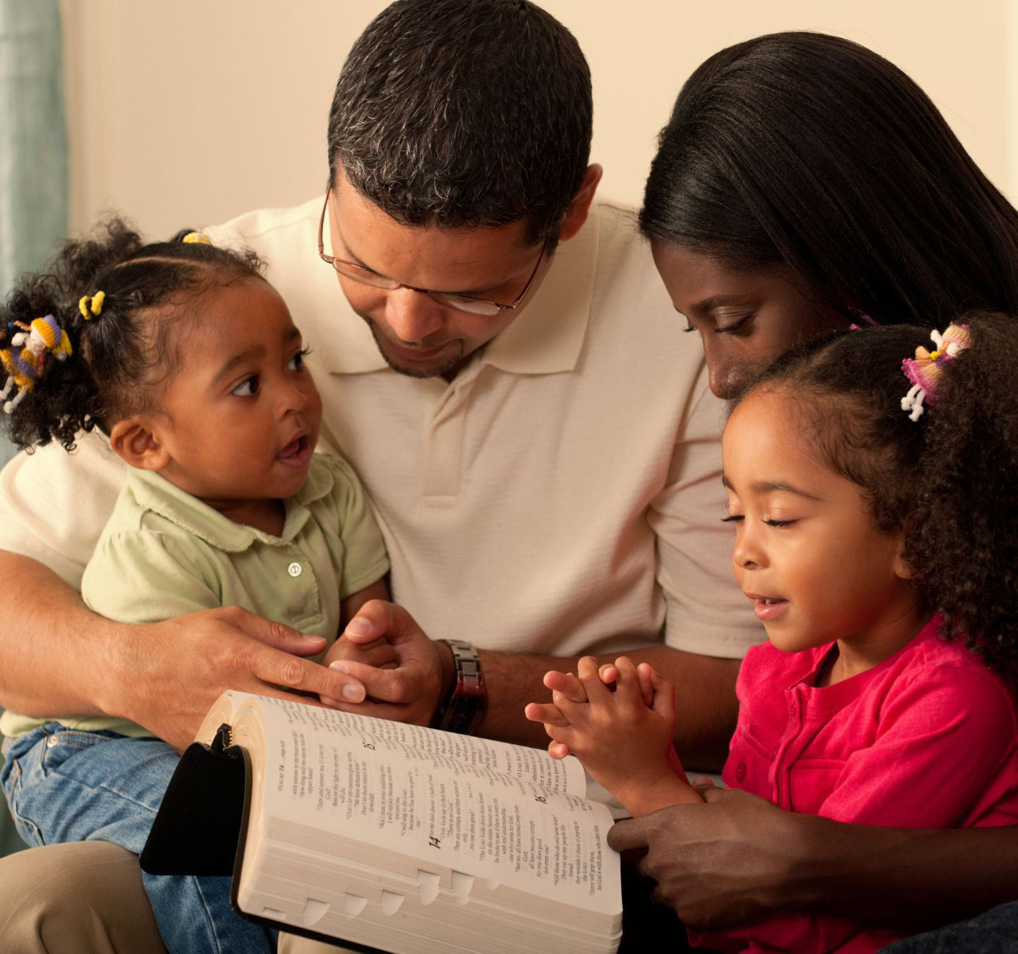 Family reading the Bible and praying together.